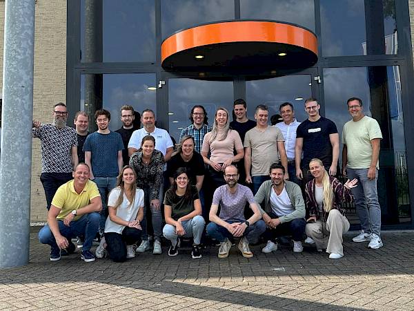 X-com medewerkers zitten aan hun bureaus en zijn aan het werken.